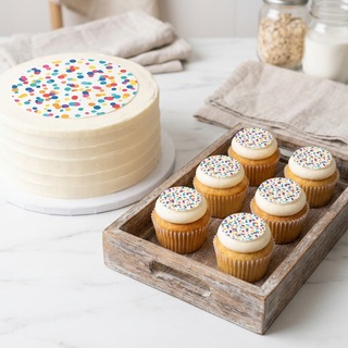 Large cake with printed topper beside cupcakes with small printed toppers